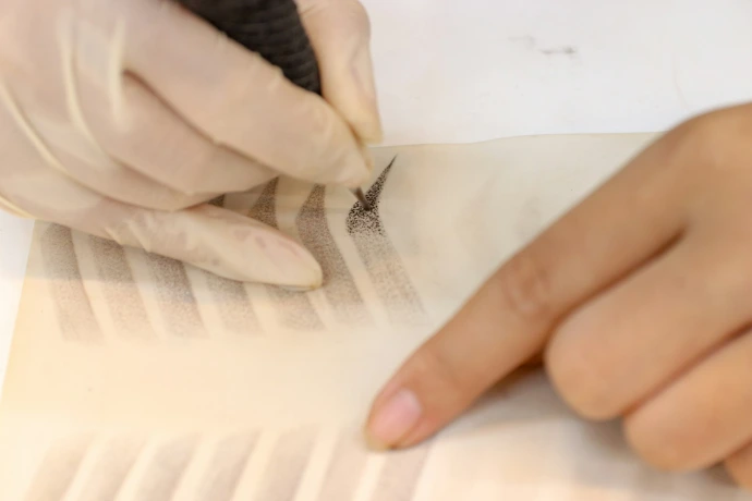 A person with a glove on writing on a piece of paper